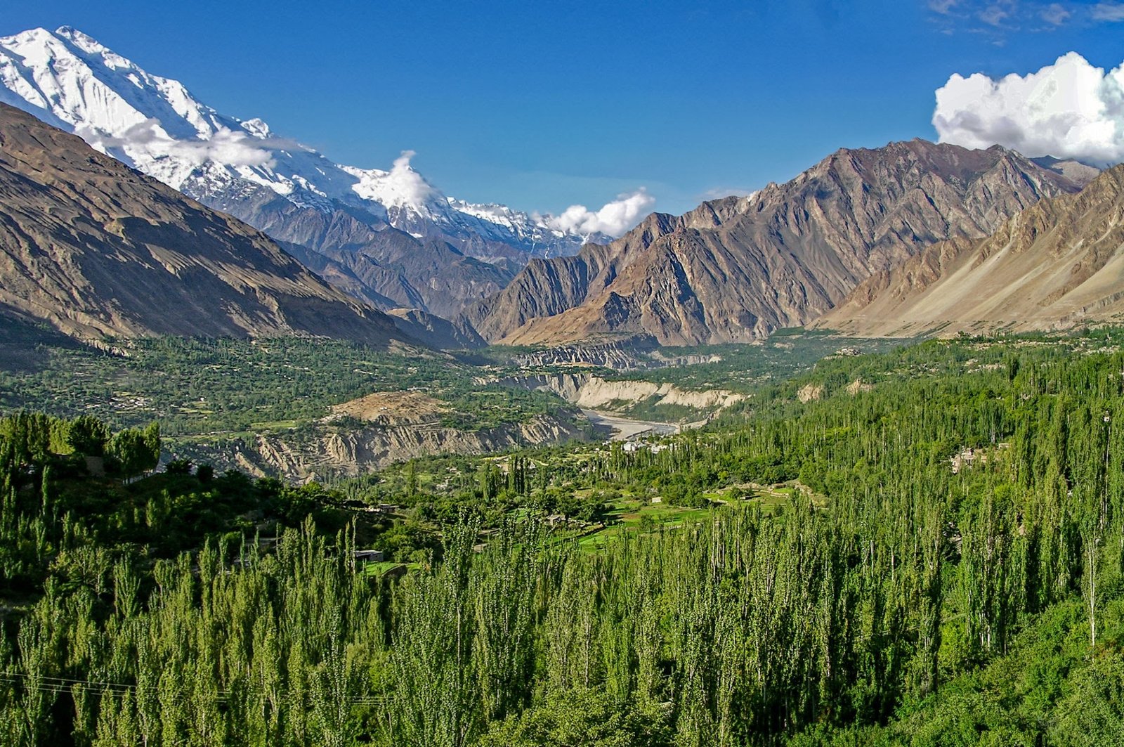 Hunza Valley: Where Heaven Kisses the Earth. A breathtaking landscape featuring majestic mountains, lush greenery, and a serene river, capturing the essence of this heavenly destination